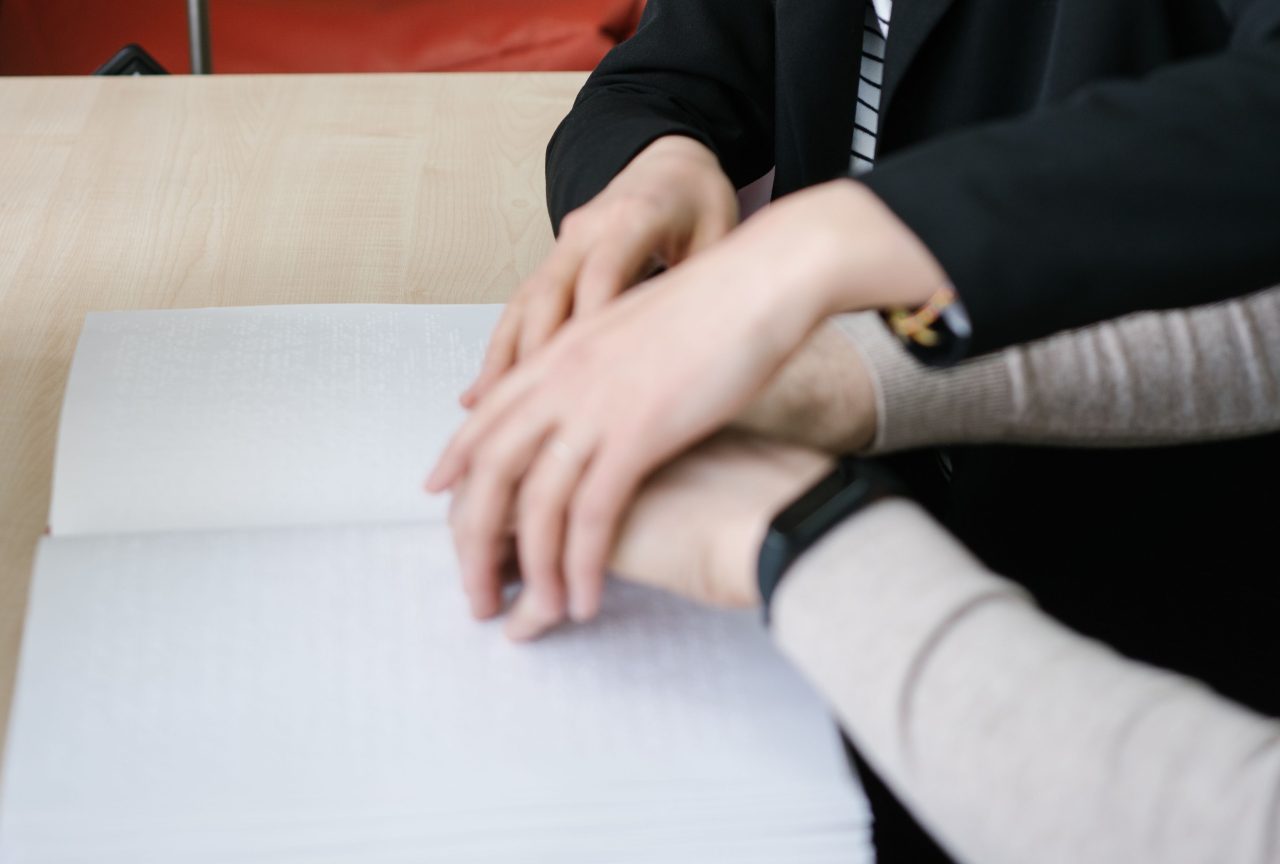Un adulte guide la main d'un élève sur son cahier : l'accompagnement pas à pas