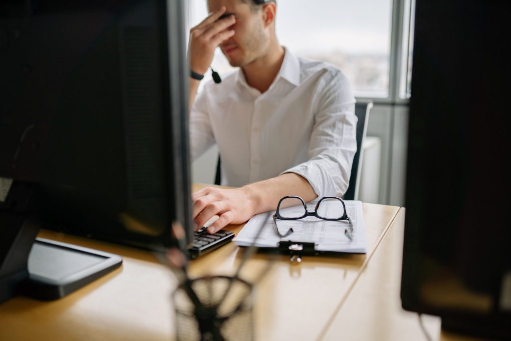 Adulte fatigué devant son écran d'ordinateur en fin de journée