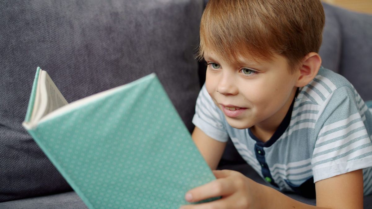 Enfant qui lit, allongé sur un canapé