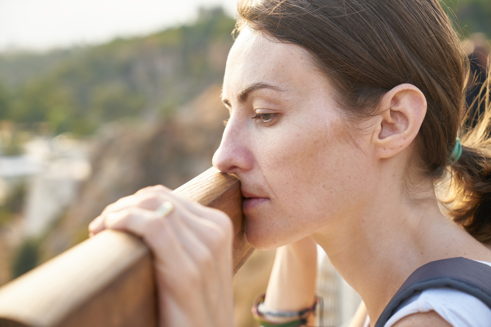 Femme épuisée, le front posé sur une rambarde, les yeux fermés