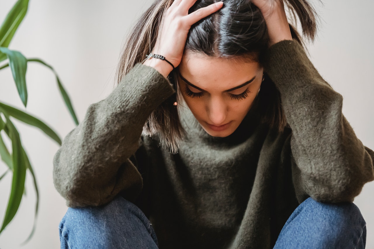 Jeune femme assise, les mains sur la tête, fatiguée