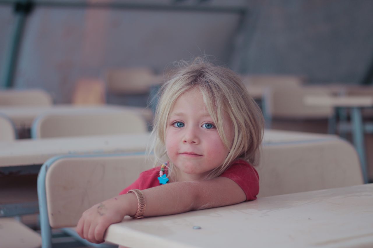 Petite fille blonde assise à son pupitre, dans une salle de classe