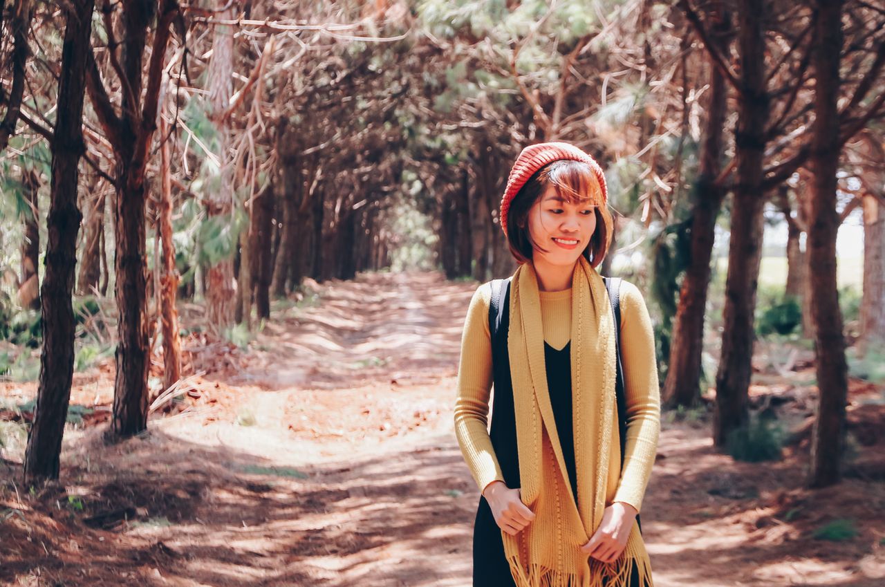 Femme souriante qui marche sur un sentier, entre les arbres