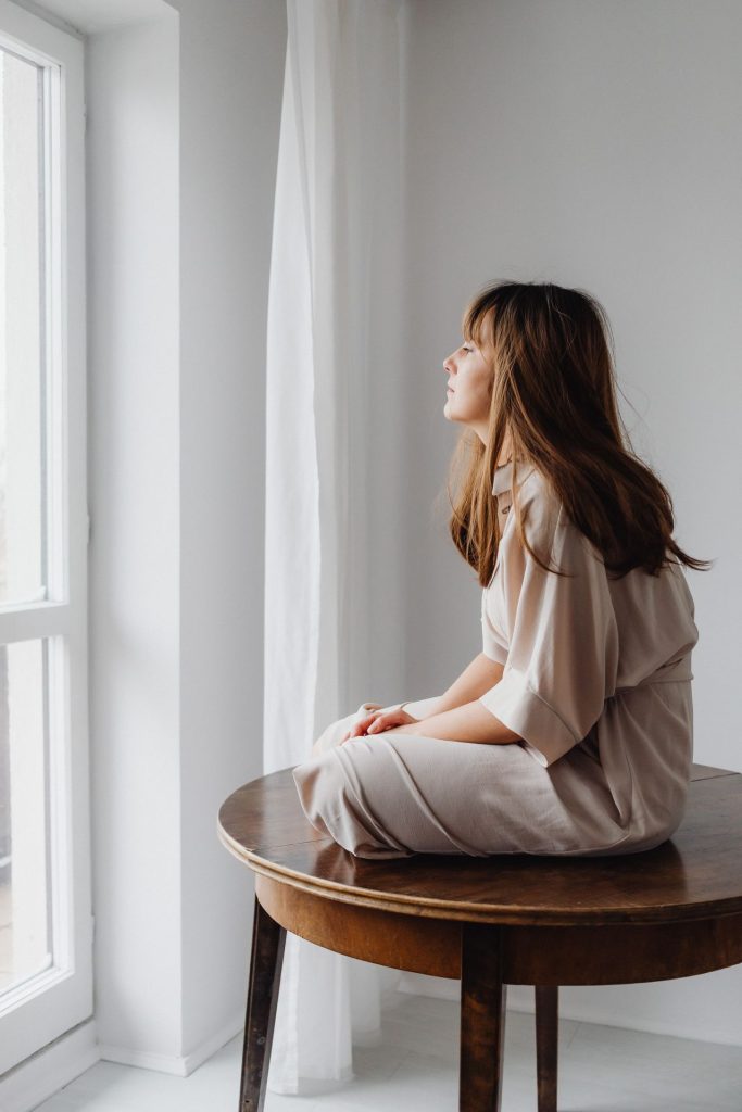 Femme assise près d'une fenêtre, dans une lumière douce