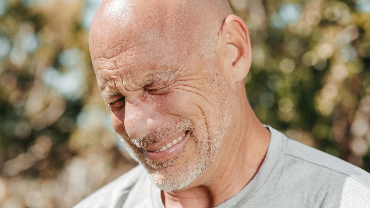 Homme au crâne rasé qui sourit, les yeux fermés au soleil