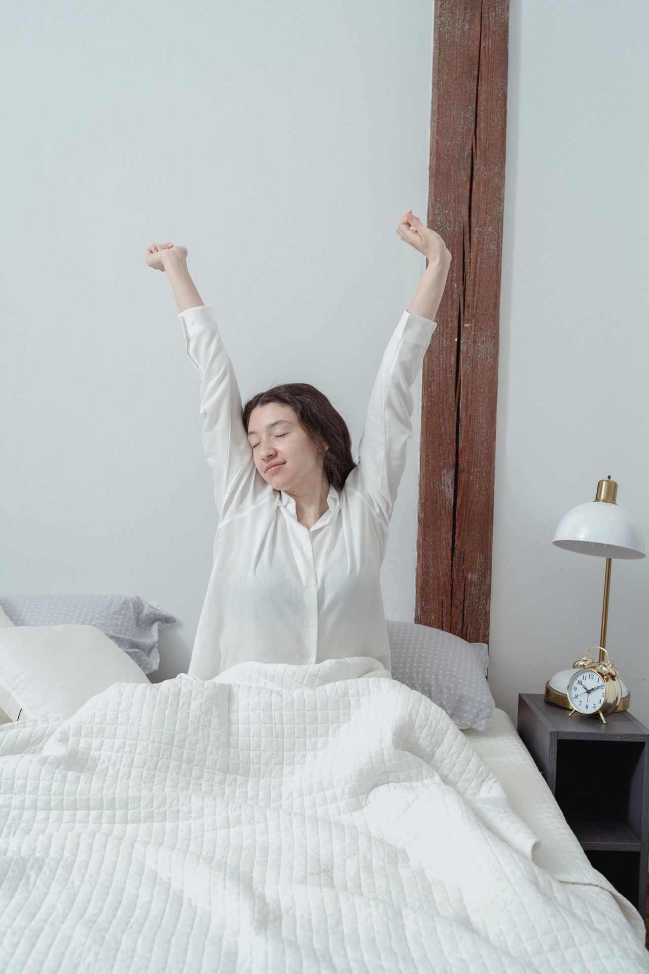 Femme reposée qui s'étire dans son lit, dans la lumière du matin