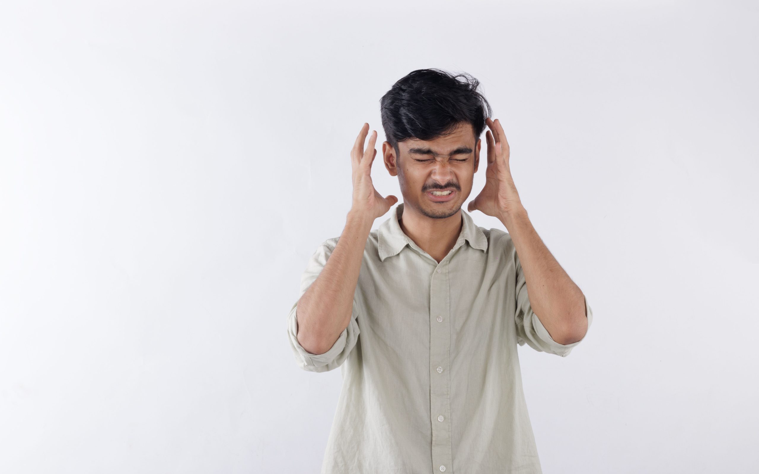 Jeune homme les mains sur les tempes, les yeux fermés, pris d'un mal de tête