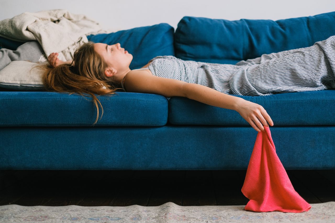 Jeune femme épuisée, allongée sur un canapé bleu