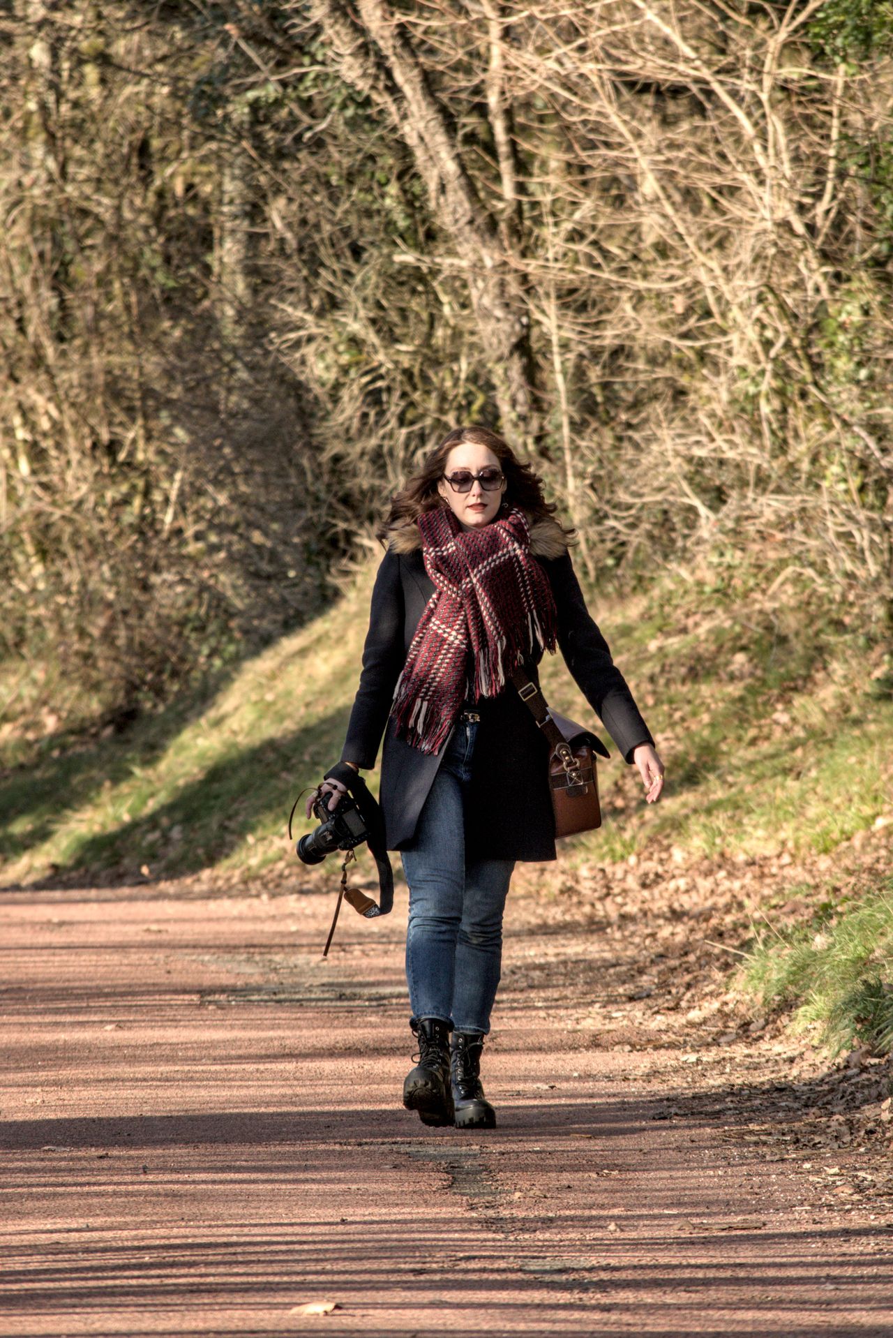 Femme en écharpe qui marche sur un chemin de campagne, au soleil d'hiver